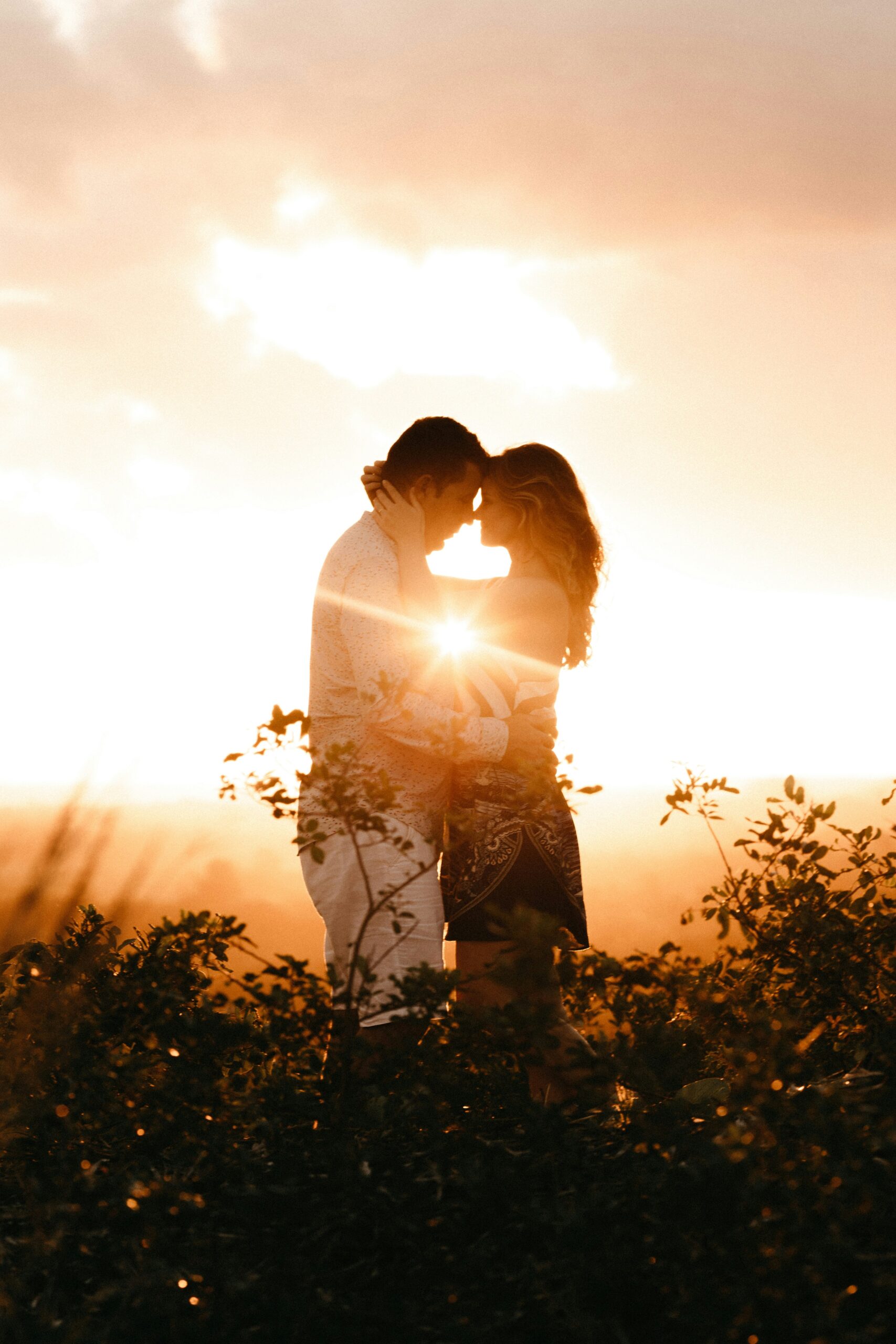 couples kissing front of sunset